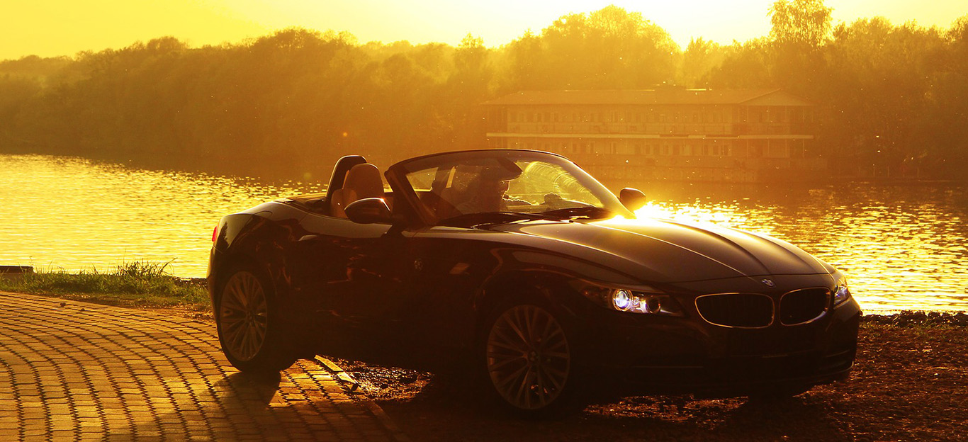 BMW Cabrio, Halbseitenansicht von vorne, stehend vor Fluss bei Sonnenaufgang
